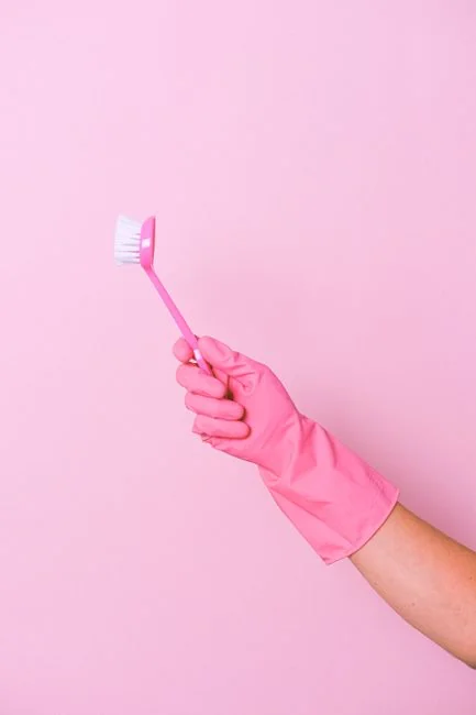 An adult woman cleaning a bathroom mirror with a spray bottle and cloth, focused on hygiene.